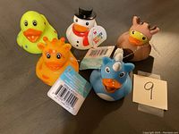 Photo showing the front and side views of five rubber ducks with different animal and character themes, including tags and barcodes on some.