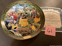 Photo showing full view of the Snow White Ever After plate alongside the Certificate of Authenticity and a lot number card.