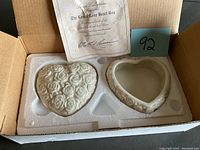 Photo showing two heart-shaped ceramic boxes and certificate in original packaging.
