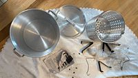 Full kit of Master Chef outdoor turkey fryer parts laid out including pot, basket, lid, black metal stand supports, and hardware on white cloth.