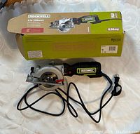 Overall view of Rockwell circular saw, power cord coiled, with original box behind it.