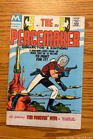 Front cover of The Peacemaker #1, showing the comic title, price, and artwork of the main comic character in action with tanks and missiles in background.
