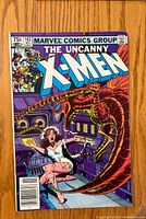 Front cover of The Uncanny X-Men #163 comic, showing a woman fleeing from a dinosaur-like creature in a mechanical setting.