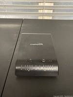 Top and front panel view of black CradlePoint MBR1200b router showing logo and LED indicators.