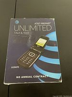 Front of box showing LG B470 flip phone and AT&T prepaid branding, highlighting unlimited talk and text and no annual contract.