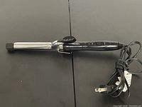 Side view of GED hair curling iron showing silver barrel and black handle with power cord.