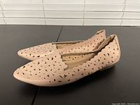 Side view of the pair of beige Unionbay women's sandals showing perforated triangular cut-out pattern and scalloped edges on upper.