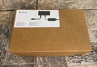 Box of Xbox Kinect power supply adapter labeled with Xbox branding and image showing the adapter in schematic form.