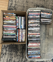 Photo of two containers filled with DVDs showing the variety and quantity of titles included in the lot.