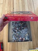 Open box of 'Afternoon with Grandma' 1000-piece puzzle showing loose puzzle pieces in plastic bag inside box.