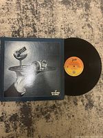 Front cover of vinyl record showing artistic image with a wine glass and spilled liquid.