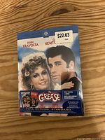 Front cover of Grease DVD showing John Travolta and Olivia Newton-John, sealed with a price sticker.