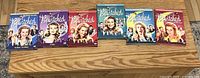 Front view of all six Bewitched DVD sets arranged side by side on a wooden surface, showing colorful cover art and main characters.