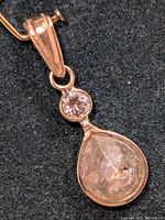 Close-up front view of pendant showing bezel-set round and pear-shaped diamonds