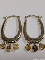 Pair of earrings laid flat showing three teardrop diamond dangles per earring