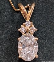 Front-facing view of pendant showing oval center diamond and three smaller diamonds above