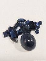 Close-up photo of a group of various cut genuine sapphires including cabochon, faceted, oval, round, marquise and rectangular stones.
