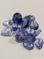 Close-up image of loose tanzanite stones highlighting variety of shapes and faceted cuts with blue and violet hues.