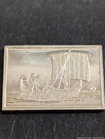 Front side of the silver bar showing the detailed embossed image of an Egyptian reed hull ship and crew.