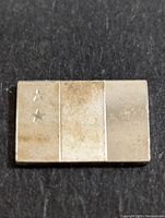 Front side of the silver bar showing three vertical sections; two with textured patterns and one smooth, with two star symbols on the leftmost section.
