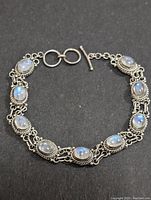Top down view of the full moonstone and silver bracelet laid flat on black background.