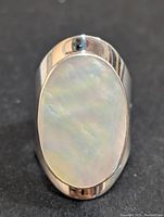 Top down view of the sterling silver ring showing the oval mother of pearl stone with iridescent finish.