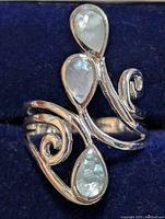 Close-up of the silver ring showing the front face with three mother of pearl teardrop stones and decorative silver swirls
