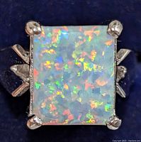 Close-up of square opalite stone ring set in silver band showing vibrant multi-colored flashes within the stone and silver prong setting.