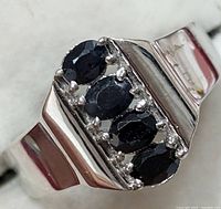 Close-up of the ring face showing the four oval blue sapphire stones set in prong settings on polished silver.