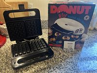 Open Salton waffle maker beside Maxim Donut Bites Maker box