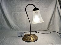 Full view of brass lily pad lamp lit with frosted shade