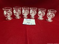 Front view of all six glass chicken egg cups on red background