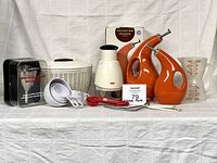 All items grouped: boxed wine funnel, salad spinner, chopper, two Rachael Ray cruets, measuring cups, measuring spoons, double measuring cup, turkey lifters