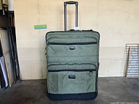 Full view of olive green rolling suitcase with handle extended