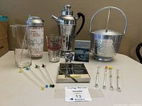 Entire lot on table including shakers, ice bucket, mixing glass, shot glass, boxed coasters and swizzle sticks