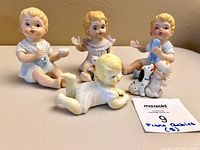 Four visible bisque piano baby figurines upright on table