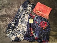 All three garments laid out: tie-dye dress, navy wrap skirt, pink sarong