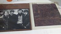 Two vinyl albums by The Band resting on a flat surface. Covers for "The Band" with band photo and "Cahoots" with artistic cover visible.