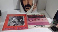 Front covers of two vinyl albums Chunga's Revenge and Hot Rats with Frank Zappa face pillow in background and third album partially visible.