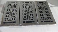 Photo showing three silver metal floor grates wrapped in plastic, arranged side by side.