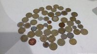 Coins spread out showing the full lot of 52 coins, including British one pound coins and other world coins.