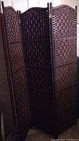Overall view of the folding room divider with three connected panels in a dark brown woven design