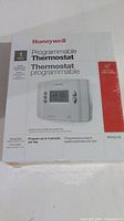 Front and side view of the Honeywell RTH221B Programmable Thermostat sealed box showing product image and details