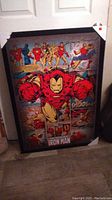 Full view of the Iron Man comic style picture in black frame leaning against wall.