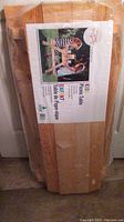 Photo of packaged flat wooden kids picnic table showing label with photo of assembled table and children sitting at it.