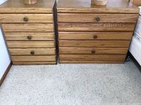 Front view of two wooden dressers with three drawers each, showing natural wood grain and metal drawer knobs.
