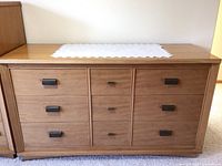 Front view of the 9-drawer wooden dresser showing all drawers and metal pull handles.