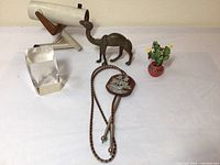 Original photo showing all items: telescope, metal camel, bolo tie, paperweight, cactus figure