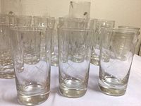 Cluster of clear vintage etched glass tumblers with cross and flower cut designs