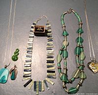 Full view of jewelry collection including necklaces, pendants, and ring on gray surface